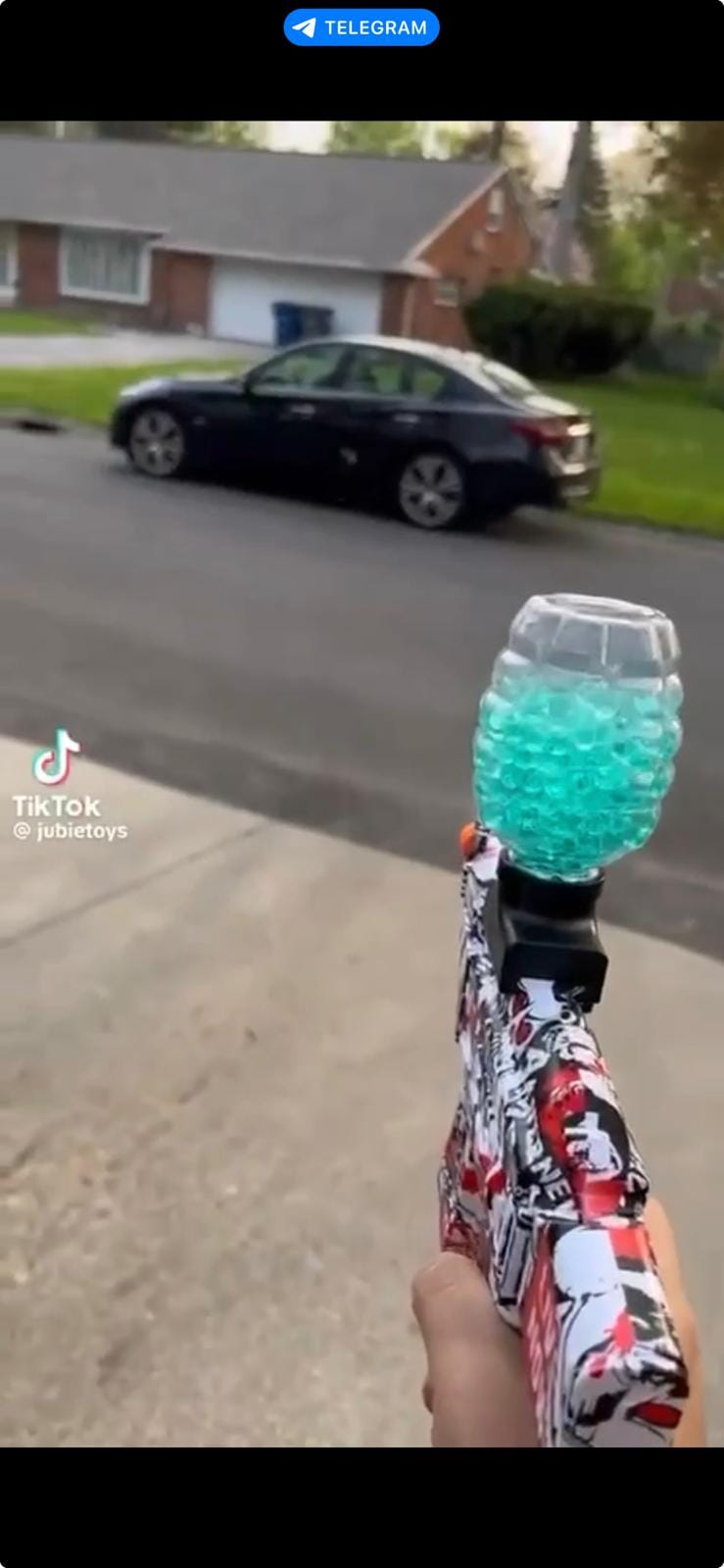 Gel blaster elettrico impugnato all’aperto, con il serbatoio trasparente carico di palline di gel verdi