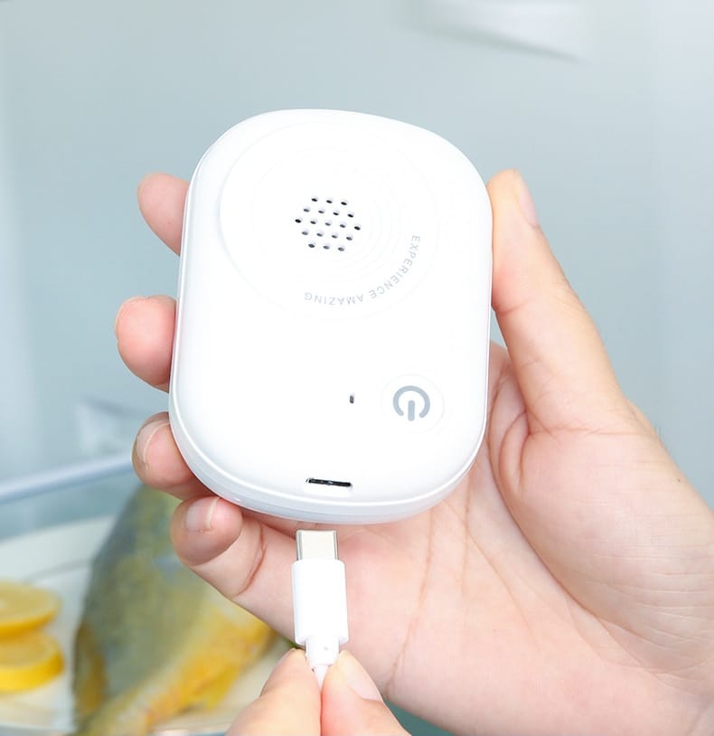 Il purificatore bianco tenuto nel palmo di una mano mentre viene collegato al cavo di ricarica USB-C