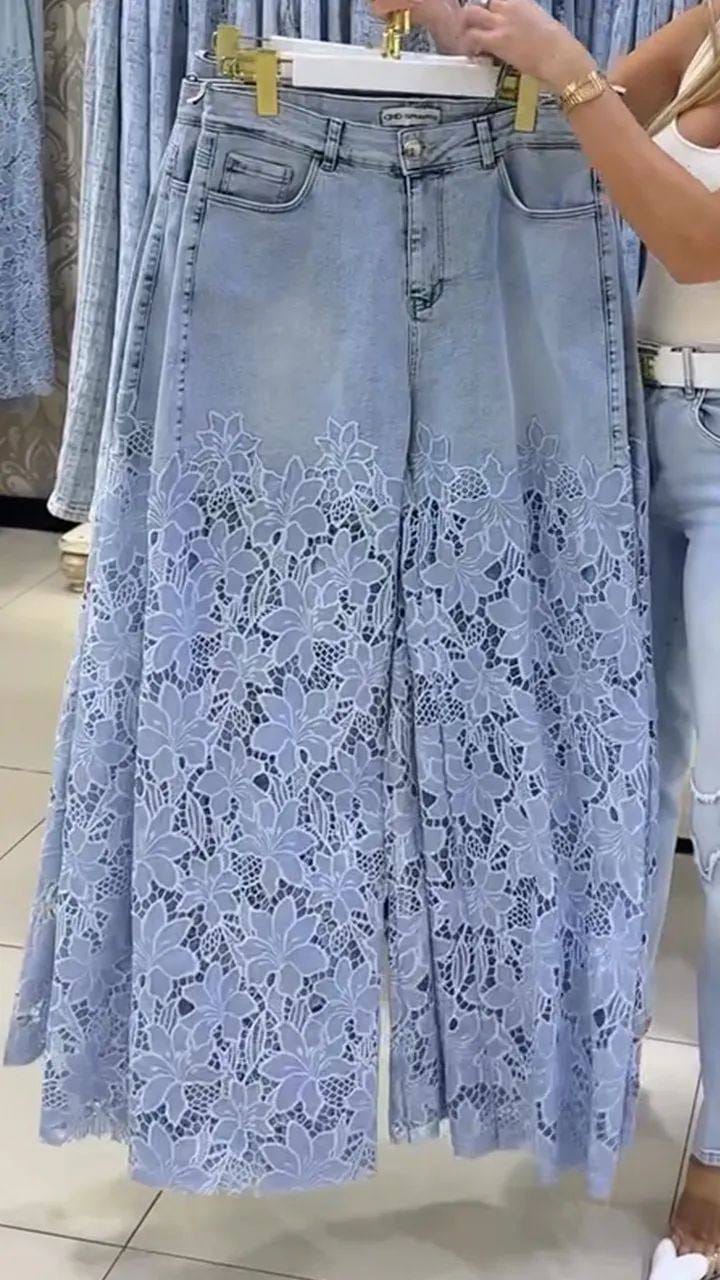Jeans chiari appesi a una gruccia in negozio, con la parte bassa in pizzo a fiori bianchi